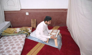 An aged man is reciting the Quran at Sunehri Masjid during Itikaf an Islamic meritorious voluntary practice of secluding oneself in a mosque for a period of time, dedicating it to worship and spiritual reflection, typically during Ramadan