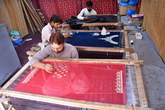 Skilled workers preparing embroidery clothes due to the increased demand for upcoming Eid-ul-fitr near Umayya colony