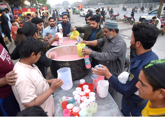 Volunteers are distributing sweetened milk and soda to thirsty passengers traveling on Shama Road during the fast-breaking period