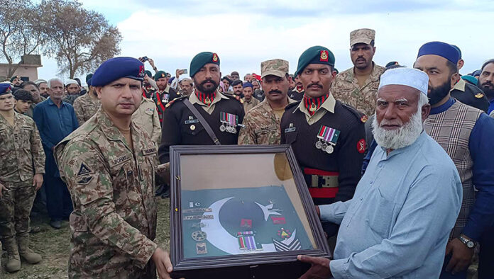 Commanding Officer 53 Field Regiment Lieutenant Colonel Sohail Akhtar presenting a uniform to Muhammad Riaz, father of Pakistan Army Naik Muhammad Usman, who who embraced Shahadat during terrorists attack on Jaffar Express