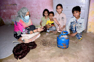 A worker woman joints bangles with the help of cylinder gas at her home to earn for livelihood in connection with International Women’s Day